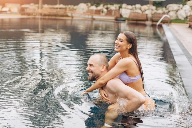 Pareja enamorada nadando juntos en la piscina