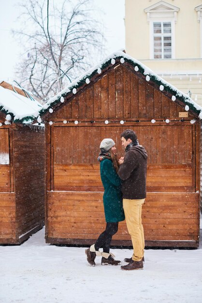 Pareja enamorada bajo la nieve Él calienta sus manos