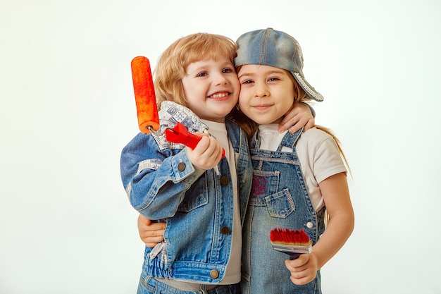 Una pareja enamorada, niños en trajes de mezclilla, un niño abrazando a una niña. En manos de una brocha y rodillo con pintura roja.