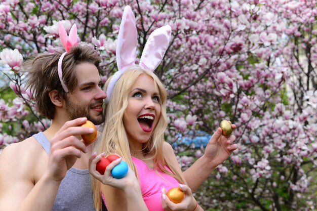 Pareja enamorada de orejas de conejo sosteniendo huevos coloridos