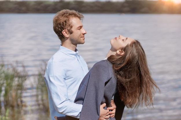 Pareja enamorada de pie junto a la orilla del lago