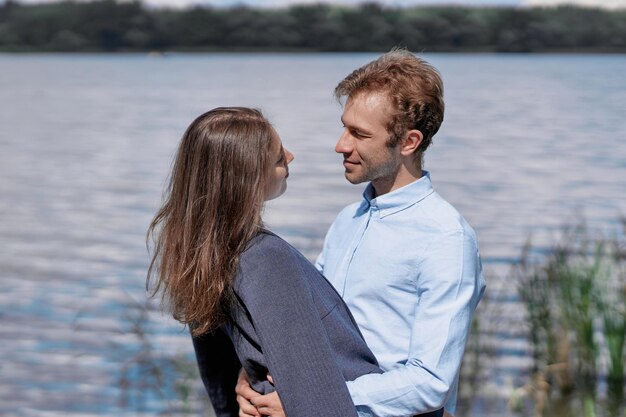 Pareja enamorada de pie junto a la orilla del lago