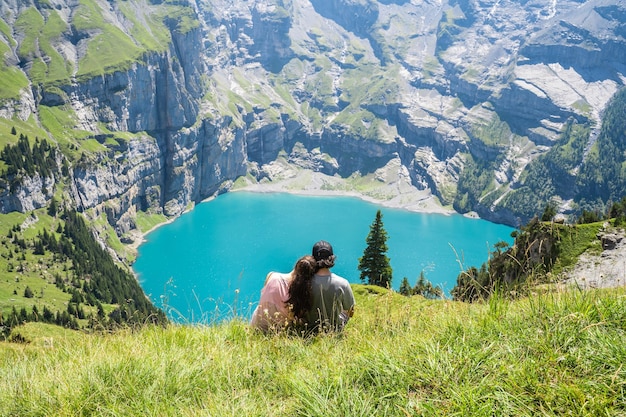 Pareja enamorada sentada en una montaña mirando un lago