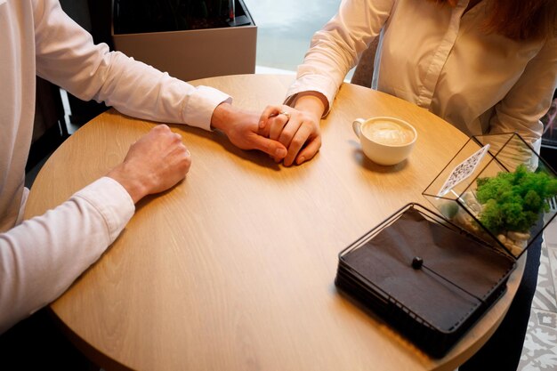 Una pareja enamorada se toma de la mano en un restaurante y bebe un delicioso café.