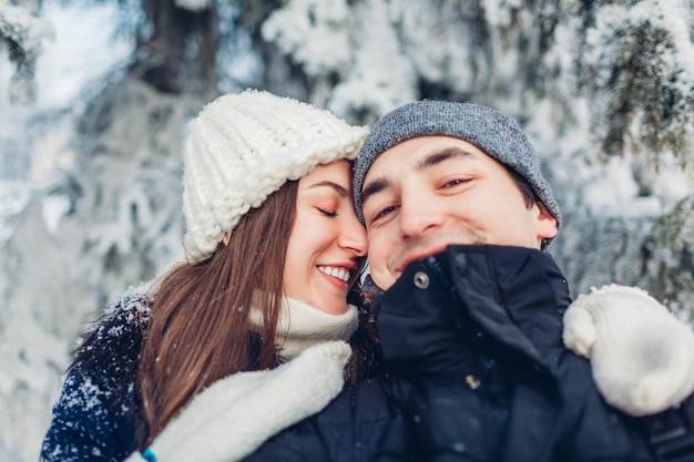 Pareja enamorada tomando selfie y abrazándose en el bosque de invierno Jóvenes felices divirtiéndose el día de San Valentín