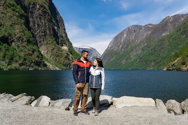 Pareja enamorada y turistas al pie del fiordo y rodeada de altas montañas en Gudvangen Noruega