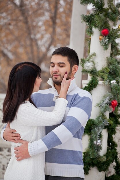 Pareja de enamorados abrazándose en cenador decorado de Navidad