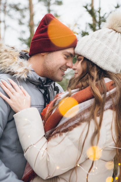 Pareja de enamorados abrazos y besos en un bosque de coníferas de invierno