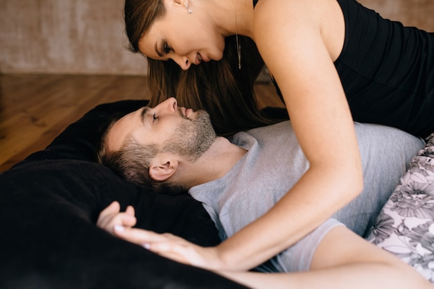 Una pareja de enamorados acostada en una cama mirando el uno al otro