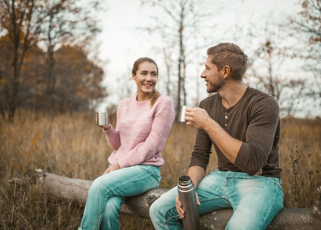 Pareja de enamorados bebe una bebida caliente en la naturaleza