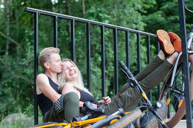 La pareja de enamorados en bicicleta en el bosque en el parque