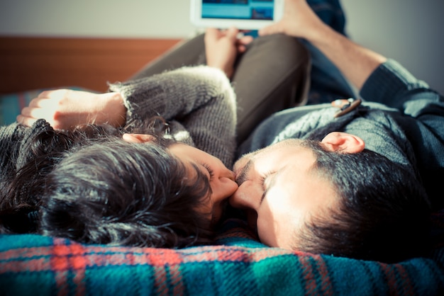 Foto pareja de enamorados en la cama usando tableta