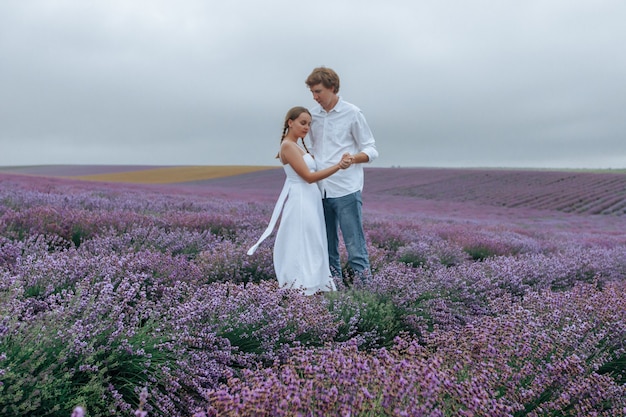 Una pareja de enamorados en un campo de lavanda en ropa blanca