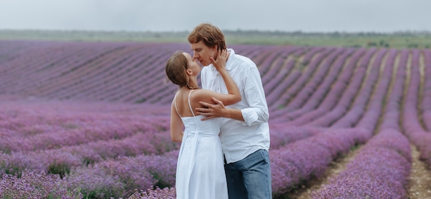 Una pareja de enamorados en un campo de lavanda en ropa blanca