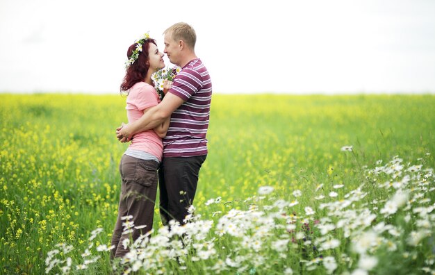 Pareja de enamorados en un campo de margaritas blancas y pasto verde