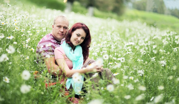 Pareja de enamorados chico y chica en un campo de margaritas blancas y pasto verde.