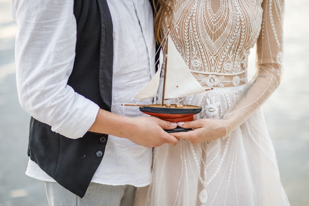 Foto pareja de enamorados en la costa. nave en mano.