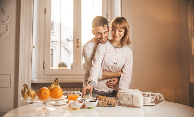 Pareja de enamorados desayunando temprano en la mañana en la cocina de su casa y pasar un buen rato.