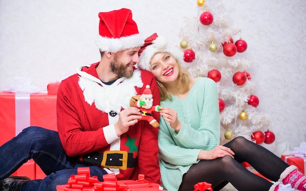 Pareja de enamorados disfruta de la celebración navideña. La familia usa sombreros de santa. Pareja amorosa abrazar sonriendo mientras espera el fondo del árbol de navidad de santa. Tiempo mágico de Navidad. Amamos la navidad.