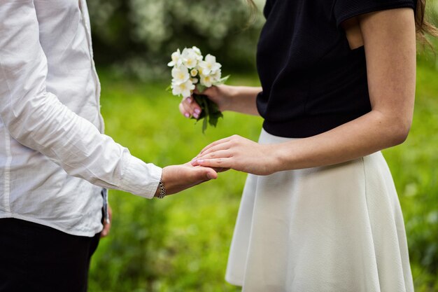 Pareja de enamorados manos tocando flor en el jardín blossomcouple manos sosteniendo una flor en un primer plano de fondo verde borroso