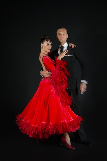 Pareja de enamorados, pareja de baile de baile en vestido rojo y esmoquin negro sobre fondo negro