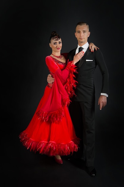 Pareja de enamorados, pareja de baile de baile en vestido rojo y esmoquin negro sobre fondo negro