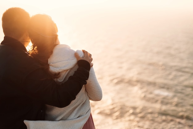 Pareja de enamorados de pie de nuevo a la cámara y mirar el océano