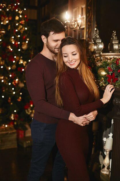 Pareja de enamorados posando cerca del árbol de Navidad