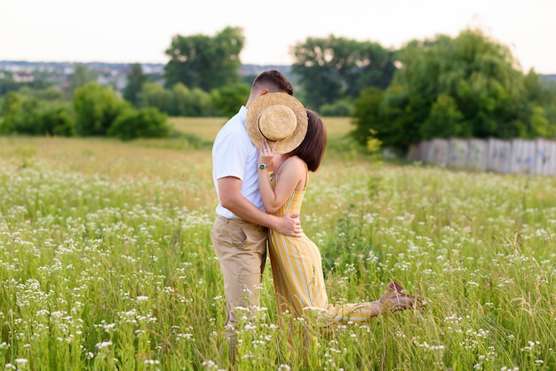 Pareja de enamorados posando en la naturaleza entre flores silvestres en verano