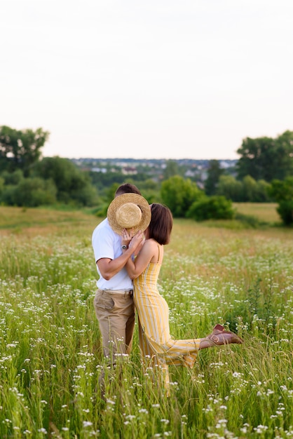 Pareja de enamorados posando en la naturaleza entre flores silvestres en verano