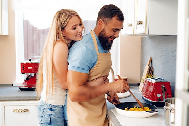 Foto pareja de enamorados preparando comida juntos en la cocina de casa