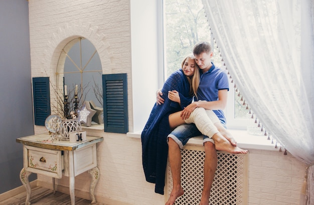 Pareja de enamorados sentados en casa en la ventana.