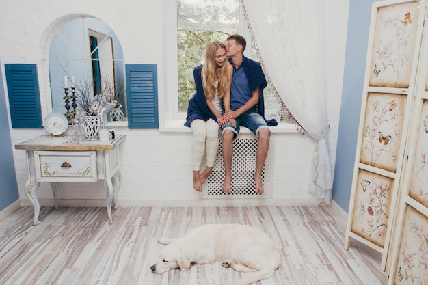 Pareja de enamorados sentados en casa en la ventana.