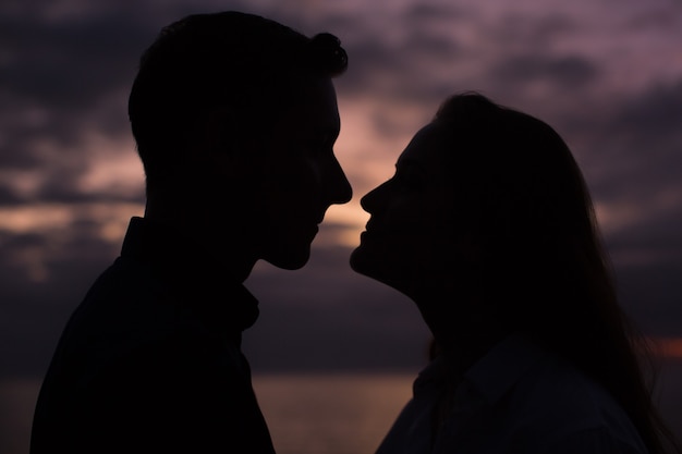 Pareja de enamorados silueta durante la puesta de sol - tocar narices