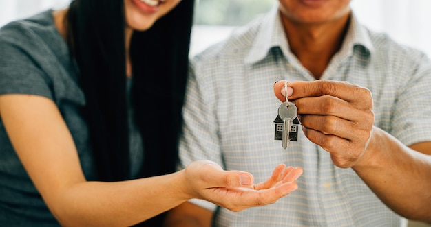 Una pareja encantada celebra la adquisición de una nueva casa mostrando las llaves de su casa