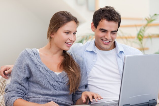 Pareja encantada usando una computadora portátil