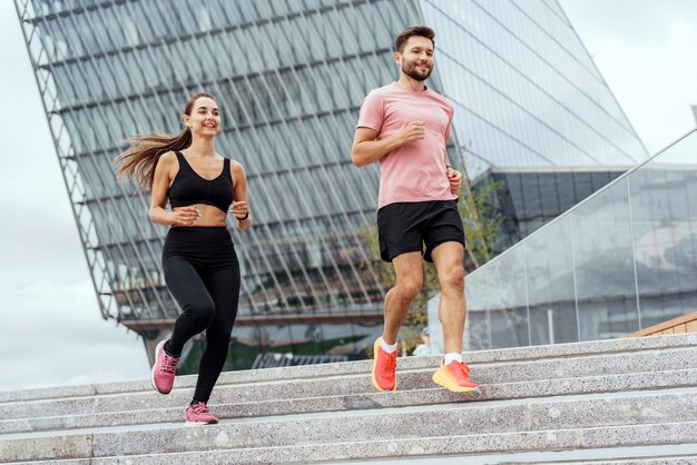 Una pareja enérgica subiendo las escaleras en un entorno urbano disfrutando de un entrenamiento conjunto