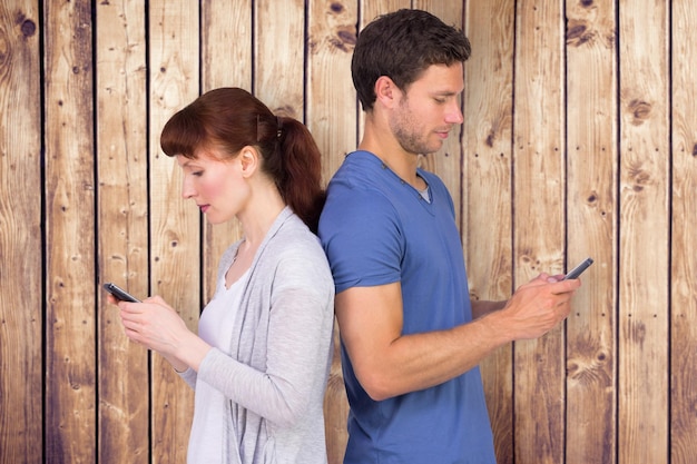 Pareja enviando mensajes de texto contra tablones de madera