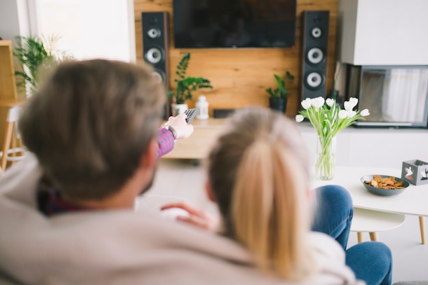 Pareja envuelta en cuadros viendo televisión