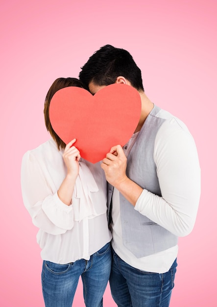 Pareja escondiendo su rostro detrás de corazón rojo