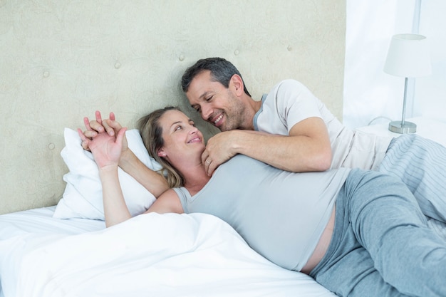 Pareja esperando acostada en la cama y charlando en su dormitorio