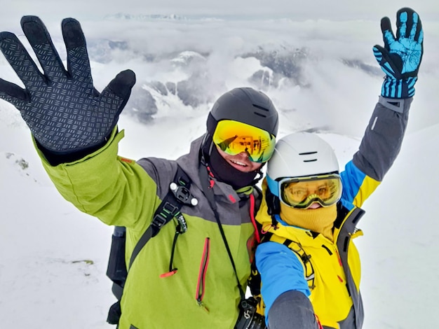 Pareja de esquiadores y snowboarders tomando selfie en la cima de la montaña