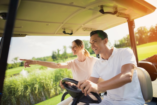 Pareja está conduciendo Golf Coche disfruta del paisaje.