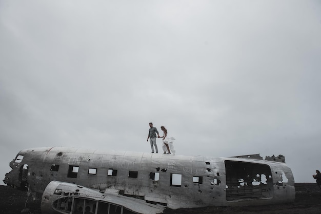 pareja está de pie cerca del avión que cayó hace mucho tiempo playa negra