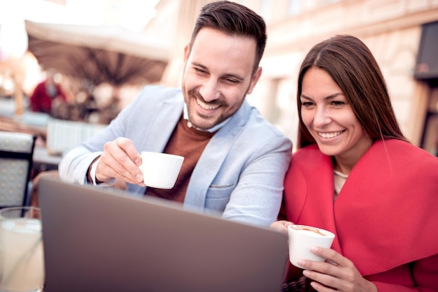 La pareja está sentada en el café y usando una computadora portátil