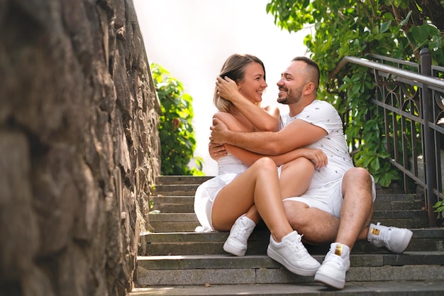 La pareja está sentada en los escalones de la ciudad y riendo alegremente