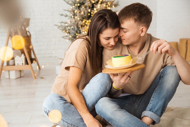 una pareja está sentada en el suelo y comiendo pastel bento con la inscripción amor es abrazos y besos