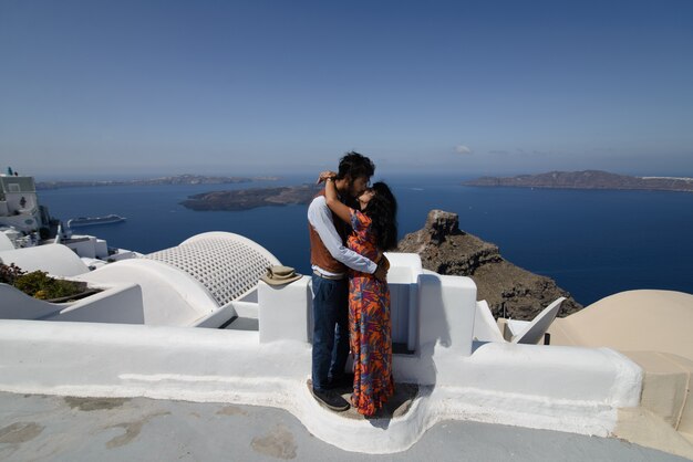 La pareja está sentada en el techo en Santorini, abrazándose y riéndose