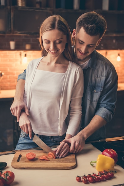 Pareja está sonriendo mientras cocina juntos en la cocina.