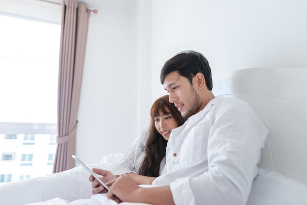 Pareja está usando tableta en la cama.